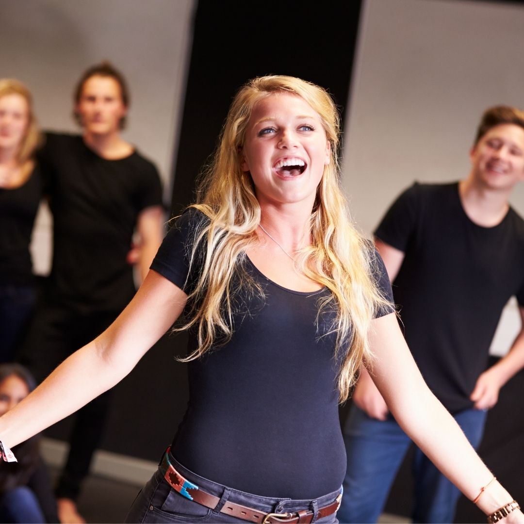blonde girl dressed in black singing for her theater class